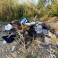 A shopping cart filled with trash surrounded by more trash near the Clark Fork River waterfront